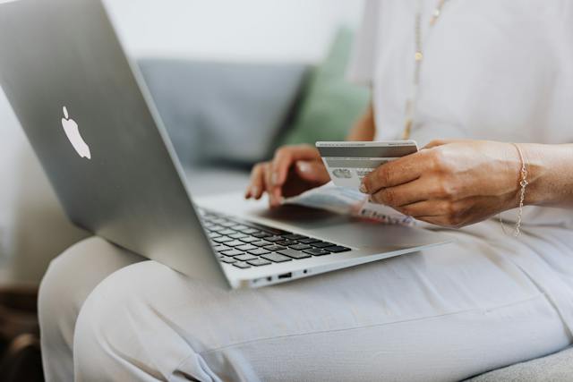 person holding a credit card and laptop to make an online payment